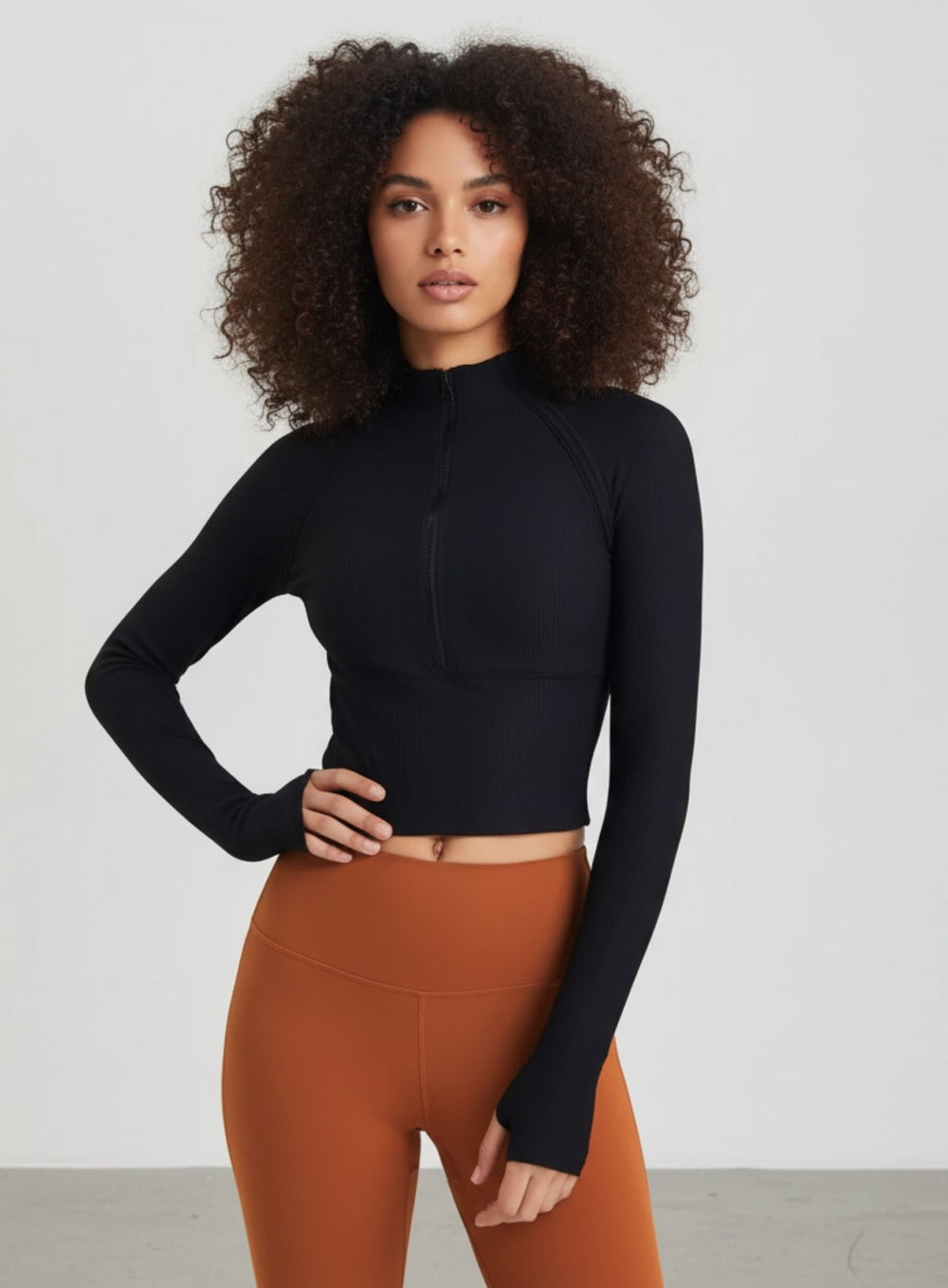 Woman wearing Black ribbed half-zip long-sleeve cropped yoga top, front view.