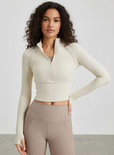 Woman wearing ivory ribbed half-zip long-sleeve cropped yoga top, front view.