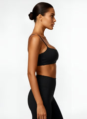 Woman wearing the CloudSense Seamless Sling Bra in black — open-back seamless sports bra with thin sling straps, sculpting fit, and smooth activewear fabric. | Vectorsportswear