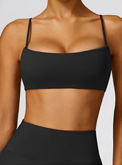 Woman wearing the CloudSense Seamless Sling Bra in black — open-back seamless sports bra with thin sling straps, sculpting fit, and smooth activewear fabric. | Vectorsportswear