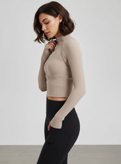 Beige ribbed half-zip long-sleeve cropped women’s yoga top with thumbholes.