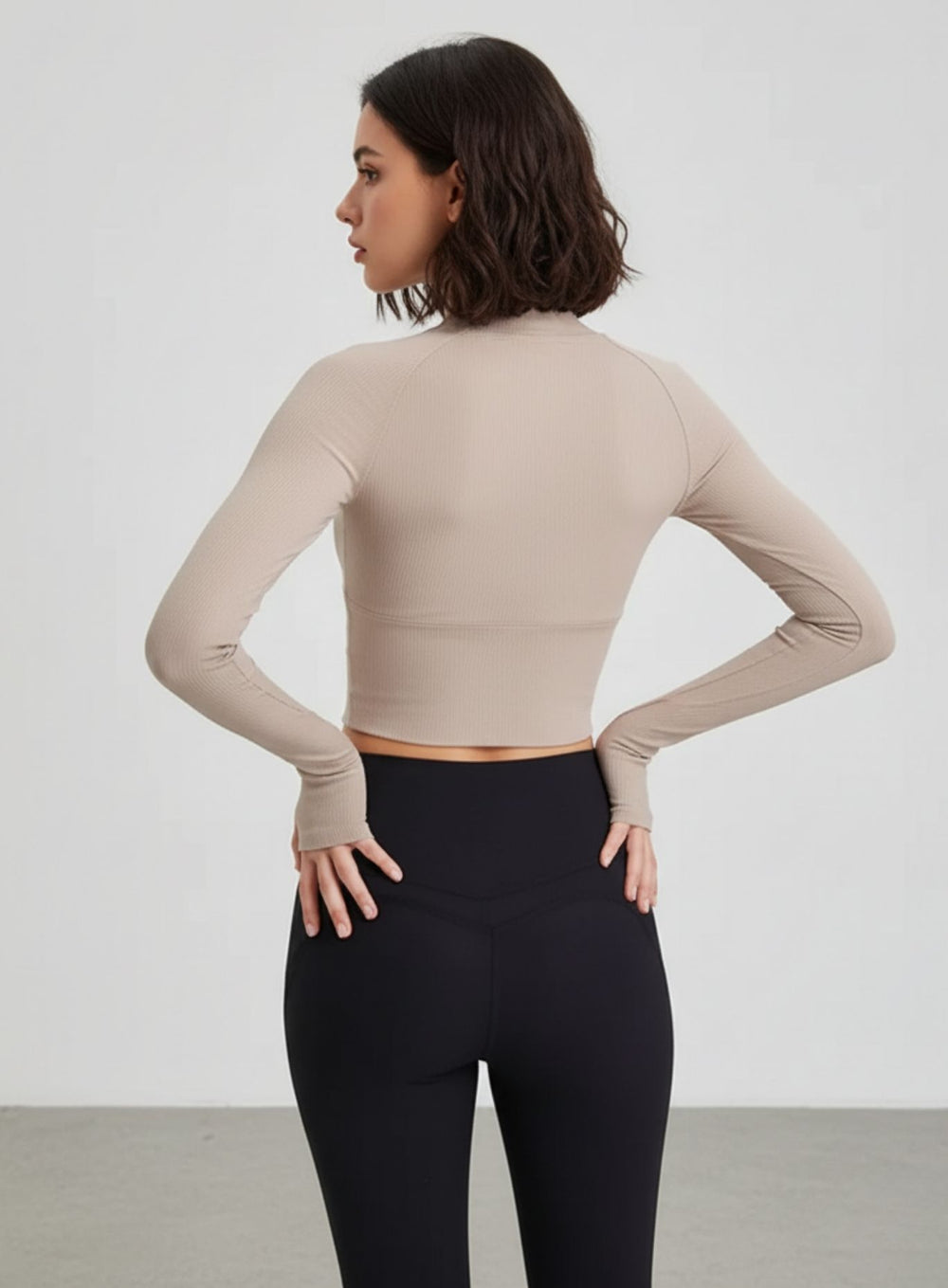 Back view of Beige ribbed cropped yoga top with raglan sleeves and thumbholes.