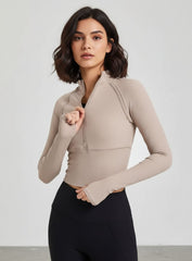 Beige women’s half-zip yoga top with thumbholes, slim fit long sleeves, cropped length.