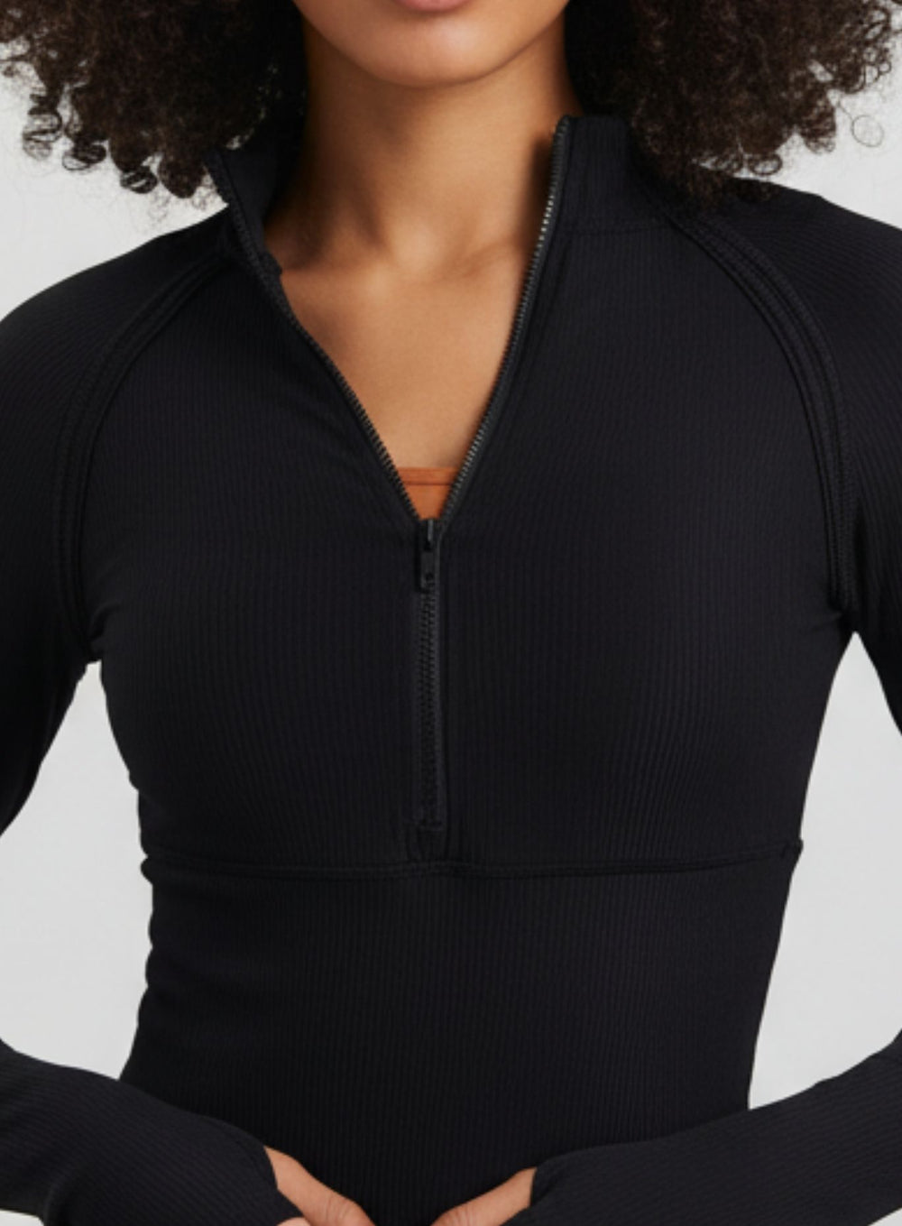Close-up of Black ribbed half-zip mock-neck yoga top, breathable quick-dry fabric.