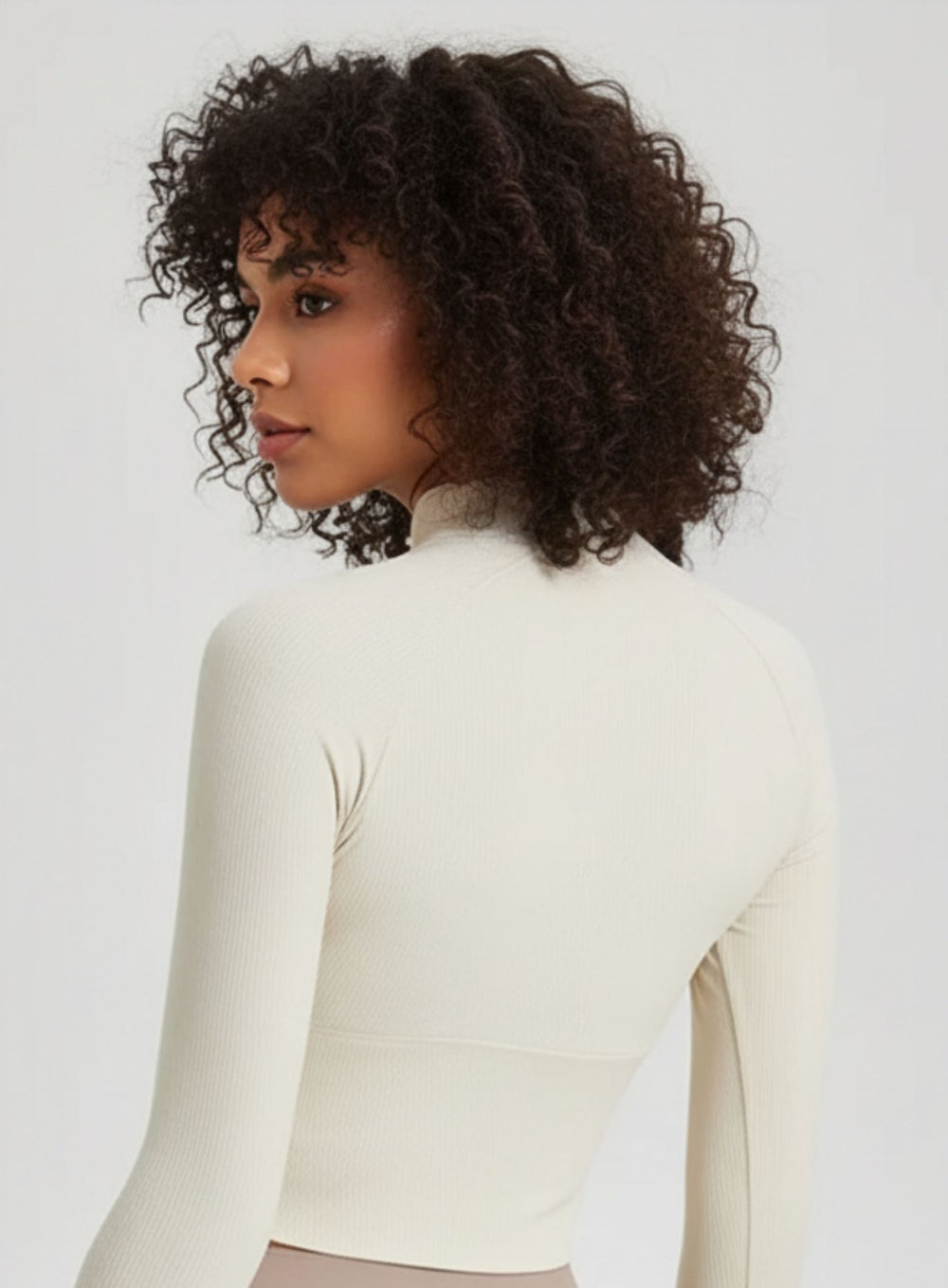 Close-up of ivory ribbed half-zip mock-neck yoga top, breathable quick-dry fabric.