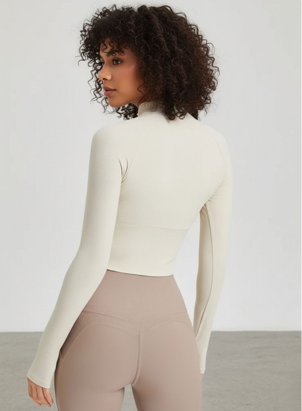 Back view of ivory ribbed cropped yoga top with raglan sleeves and thumbholes.