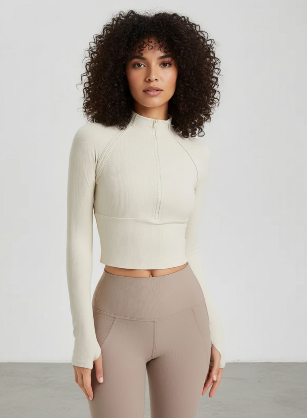 Woman wearing ivory ribbed half-zip long-sleeve cropped yoga top, front view.