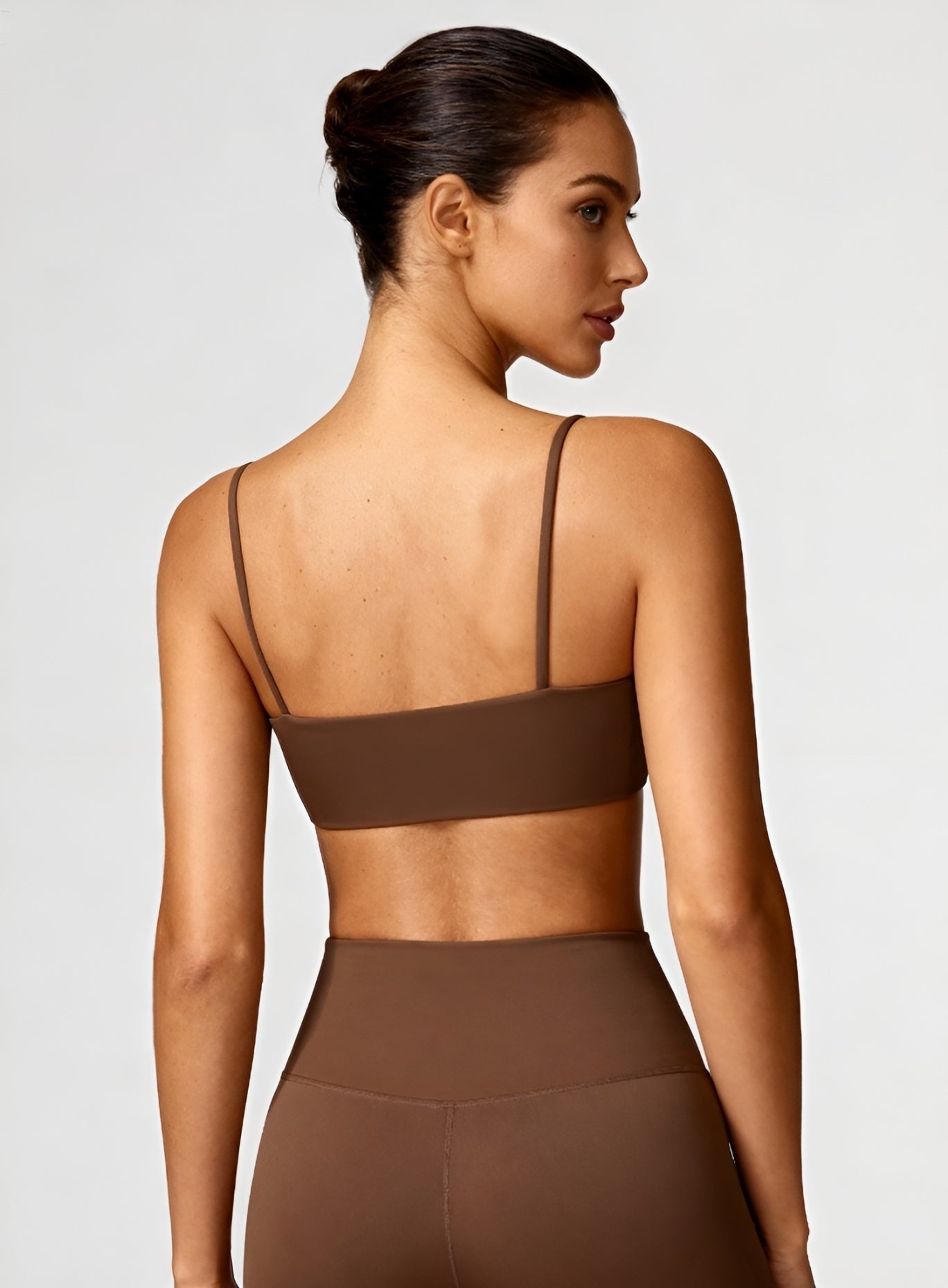 Rear view of model wearing black CloudSense Seamless Sling Bra — seamless open-back design with thin sling straps and sculpting performance fabric. | Vectorsportswear