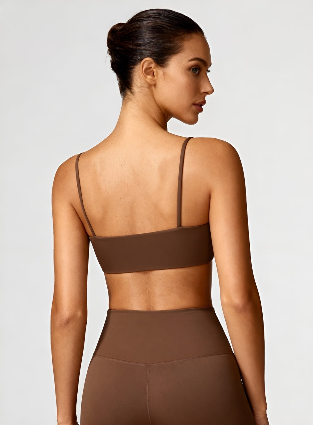 Rear view of model wearing black CloudSense Seamless Sling Bra — seamless open-back design with thin sling straps and sculpting performance fabric. | Vectorsportswear